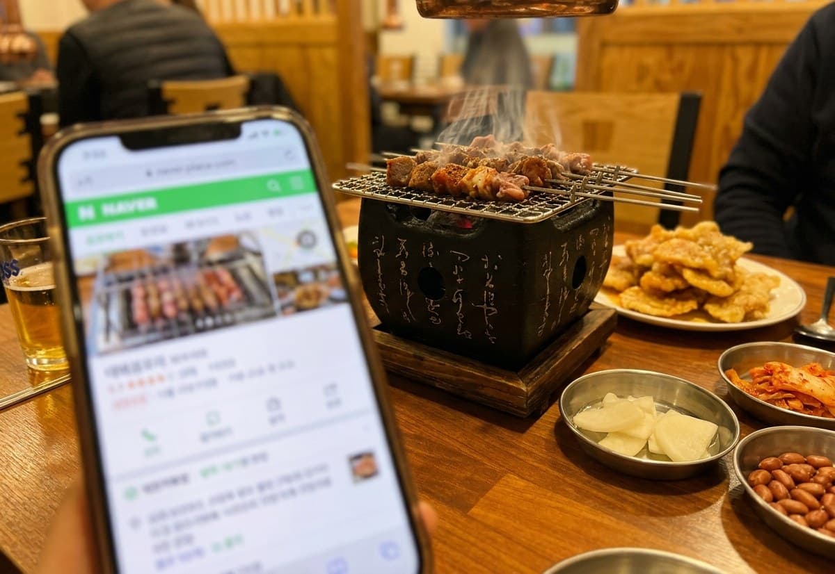 강사가 운영하는 반포양꼬치 테이블에서 휴대폰으로 네이버 플레이스를 확인하는 모습